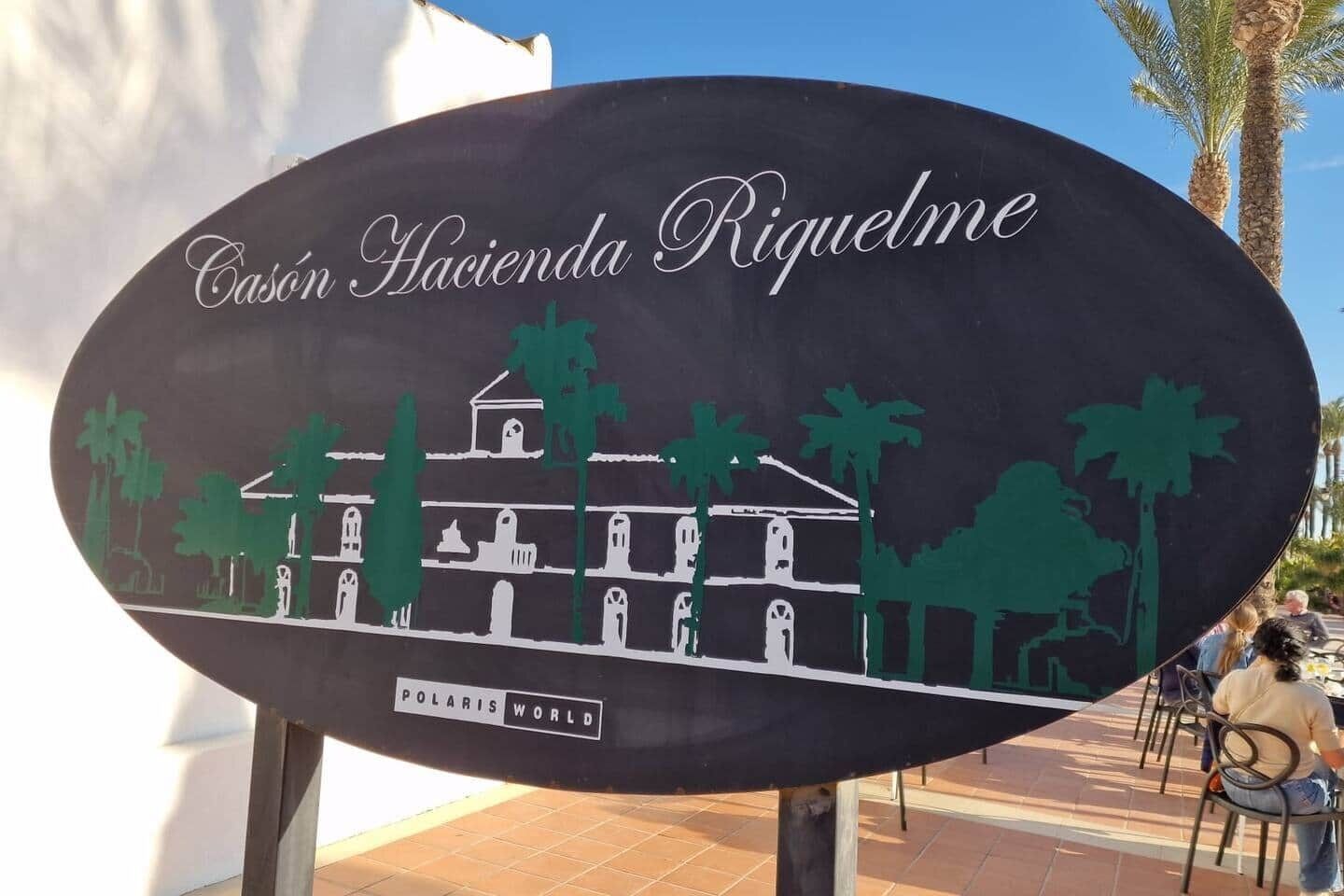 Señal de Casón Hacienda Riquelme con la silueta de un edificio y palmeras.