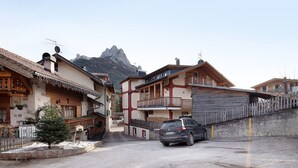 Un village de montagne avec des maisons traditionnelles en bois, une voiture garée et un sol recouvert de neige.