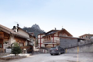 Un pueblo de montaña con casas de madera tradicionales, un coche aparcado y suelo cubierto de nieve.