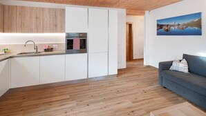 Une cuisine moderne avec des armoires blanches, un évier en acier inoxydable et un torchon à carreaux rouges et blancs.