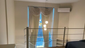 A bedroom with a bed, a window with curtains, a balcony, and an air conditioning unit. - Apartamento 511 Saint Sebastian Flat (Jaraguá do Sul)