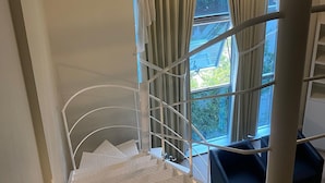 A staircase with a metal railing, beige curtains, and a view of greenery outside. - Apartamento 511 Saint Sebastian Flat (Jaraguá do Sul)