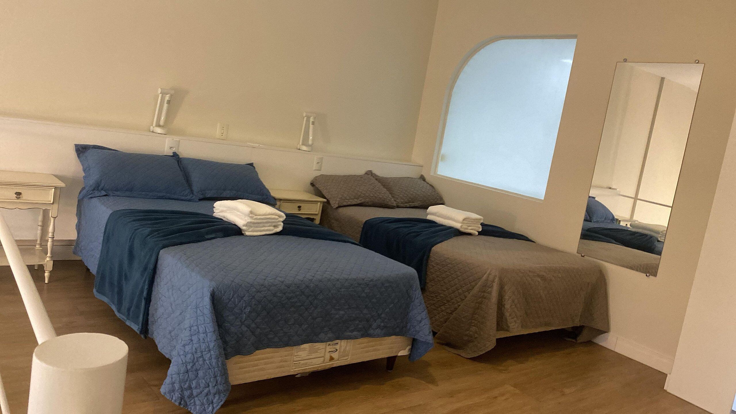 Une chambre à coucher avec deux lits, chacun recouvert d’une couverture bleue et marron, et une petite table de chevet avec une lampe.