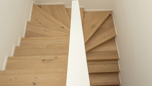 Een houten trap met witte wanden en een ronde plafondlamp.