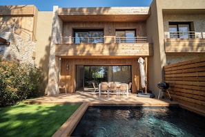 A modern two-story house with a pool, outdoor seating, and a stone facade. - Villa Testa (Lecci)