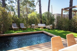 Une piscine avec des chaises longues et une terrasse en bois.