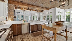 Una cocina amplia con una isla grande, armarios de madera y una pared de acento de piedra.