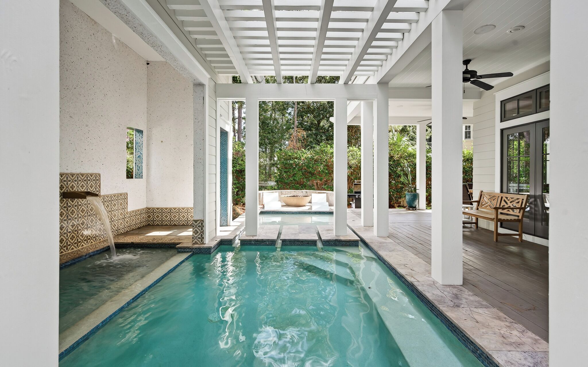 A pool area with a pergola, seating, and a view of the outdoors.