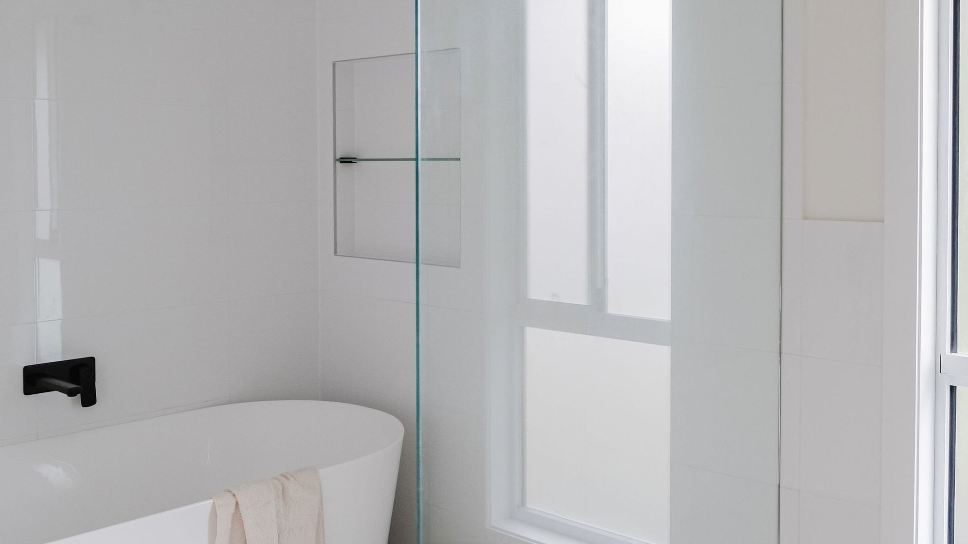 Ein modernes Badezimmer mit einer Duschkabine aus Glas, einer weißen Badewanne und einer Glastür.