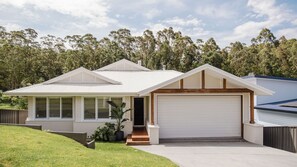 A single-story house with a garage, a covered porch, and a well-maintained lawn. - The Lake Escape - Sauna & Spa (Conjola Park)