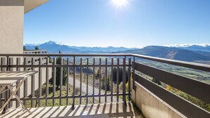 A balcony with a metal railing overlooking a mountainous landscape.