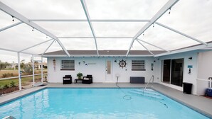 En overdækket pool med tag, et lille siddeområde og en dør til en overdækket terrasse.