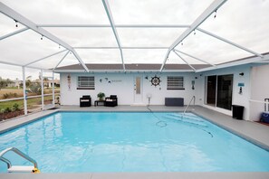 A covered swimming pool with a roof, a small seating area, and a door leading to a covered patio. - 3-bedroom house in perfect Rotonda West with cool AC (Rotonda West)