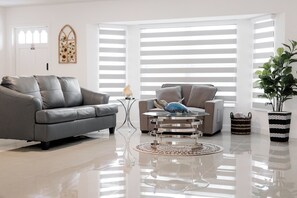 A modern living room with a grey sofa, a grey armchair, a round coffee table, and a potted plant. - 3-bedroom house in perfect Rotonda West with cool AC (Rotonda West)