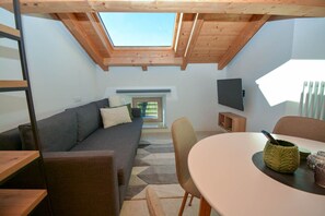 Un interior moderno con tragaluces, un sofá, una mesa de comedor y un televisor.