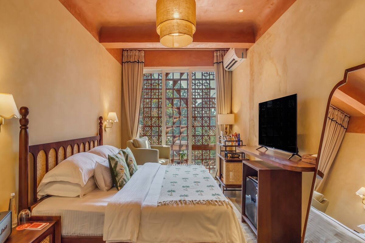 A bedroom with a wooden bed, a desk with a television, and a window with a decorative screen.