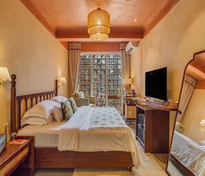 Una camera da letto con un letto di legno, una scrivania con televisore e una finestra ornata da un pannello decorativo.