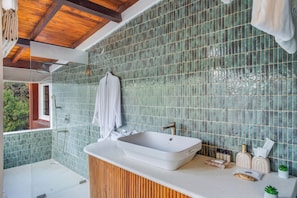 Un bagno con un ampio lavabo rettangolare, un mobile bagno in legno e una zona doccia.