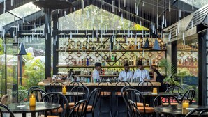Un restaurant situé à l’intérieur, avec un bar, des tables, des chaises et diverses bouteilles exposées sur des étagères.