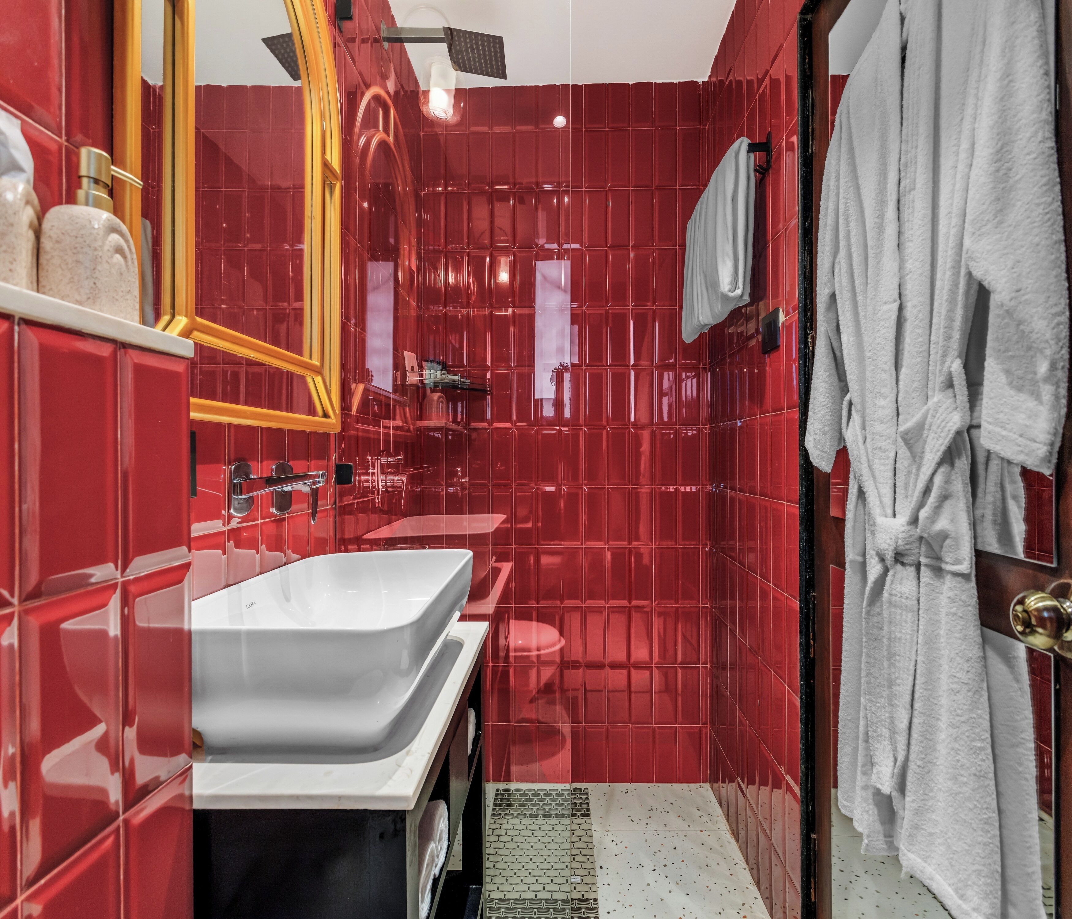 A bathroom with red tiled walls, a white sink, and a towel rack.