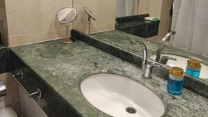 Une salle de bain avec un lavabo en marbre, un miroir et un rideau de douche.