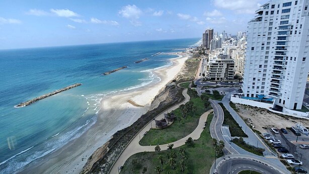 Un paysage urbain côtier avec une plage, une route sinueuse et des immeubles de grande hauteur.