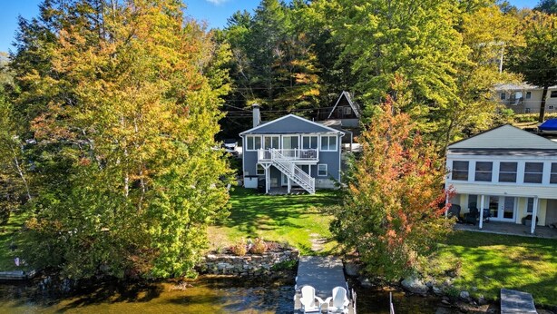 A house with a dock and two boats, surrounded by trees and a body of water. - Sawyer Lake NH, Lake & Ski – 4BR, all the amenities for Year-Round Adventure! (Gilmanton)