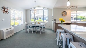 A modern kitchen with a dining area, large windows, and a view of the neighborhood. - Kick Back on Kendall (Nelson)