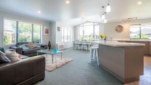 Un salon moderne comprenant un canapé, une table basse et un coin repas avec des chaises.