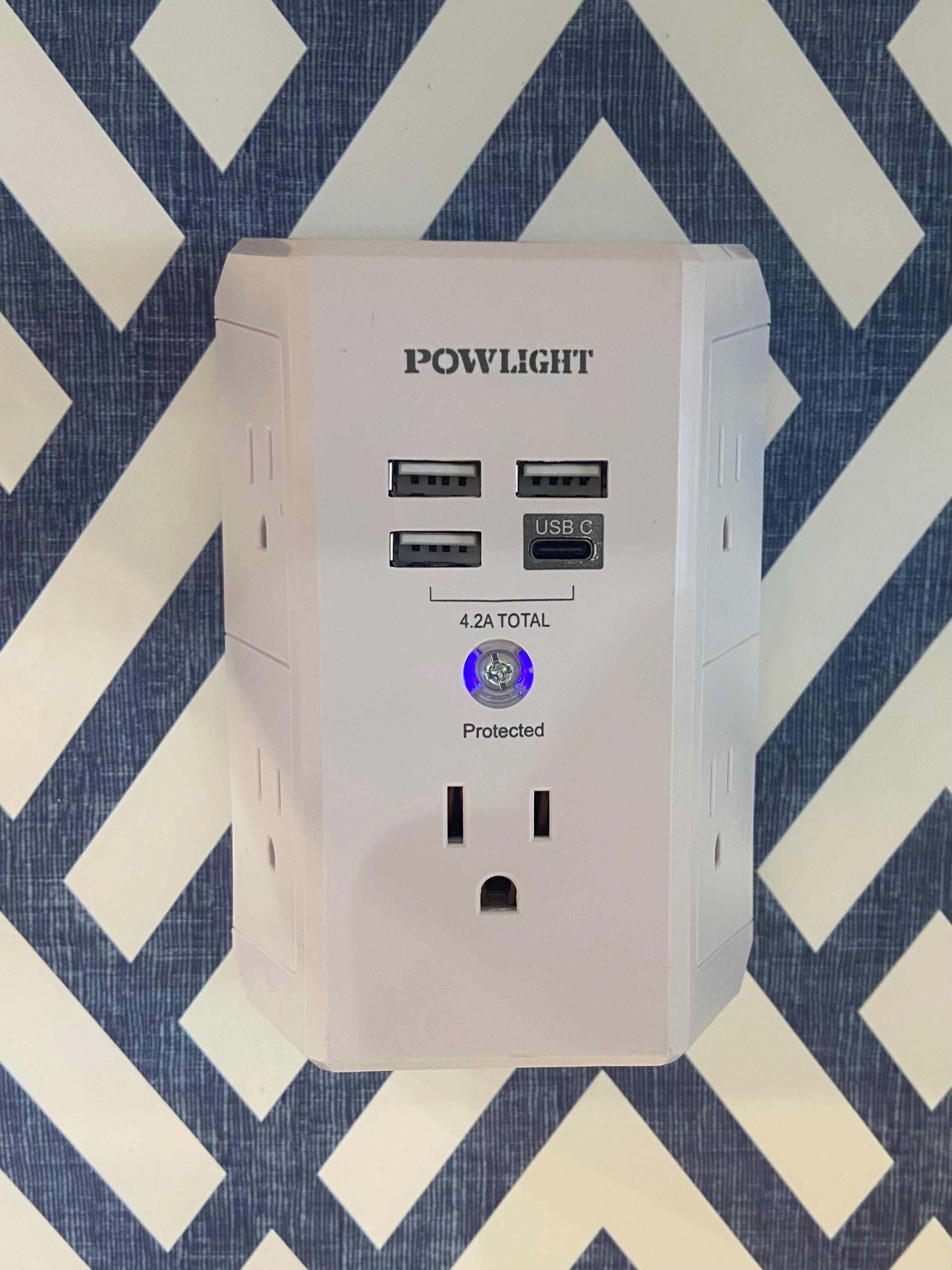En hvid strimlel med flere USB-porte og en USB-C port, mærket "POWLIGHT" og "Protected".