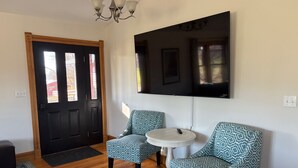 A room with a black door, a white round table, and two patterned chairs.