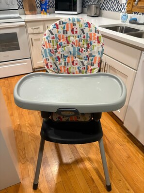 Une cuisine avec une chaise haute dont l’assise est ornée d’un motif coloré représentant l’alphabet.