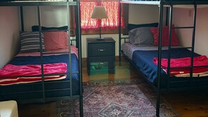 A dormitory room with bunk beds, a small desk, and a patterned rug.