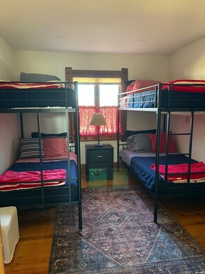 Une chambre de dortoir avec des lits superposés, un petit bureau et un tapis à motifs.