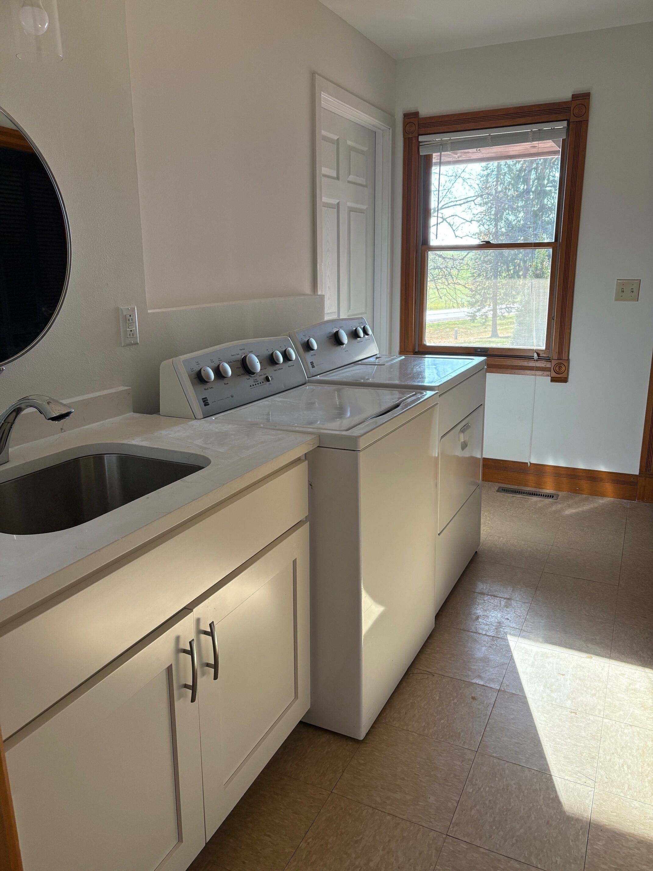 A laundry room with a washing machine, a dryer, and a sink.