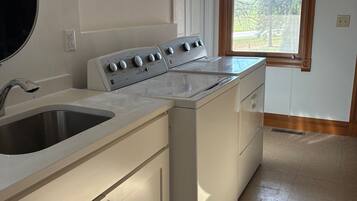 A laundry room with a washing machine, a dryer, and a sink.