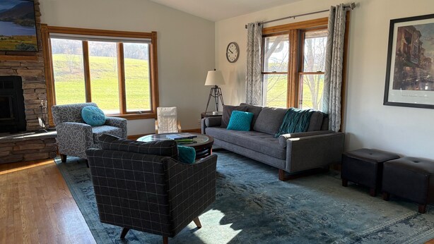 A living room with a stone fireplace, a sofa, a chair, a coffee table, and a rug.