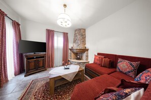 Ein Wohnzimmer mit Fernseher, Sofa und Kamin.