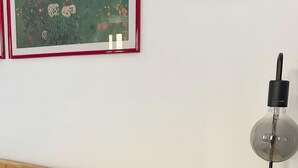 A bedroom with a wooden bed, a nightstand with a lamp, and a framed floral artwork on the wall. - Judith Room (Ciriè)