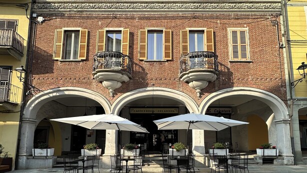 A courtyard with stone flooring and outdoor seating with umbrellas. - Judith Room (Ciriè)