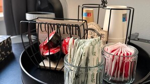 A black tray with a money organizer, a glass jar, and a small container holding red and white items. - Judith Room (Ciriè)