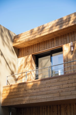 Ein Gebäude mit einer Holzfassade, einem Balkon und einem Fenster.