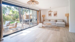 A spacious living area with a large sliding glass door leading to an outdoor patio, a sofa set, and two pendant lights. - Villa Cala Rossa (Lecci)