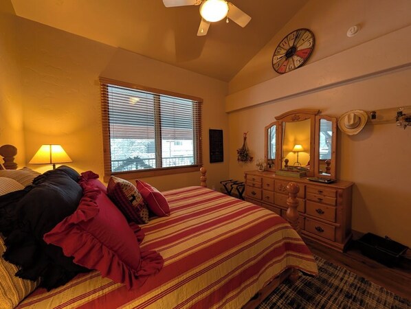 A bedroom with a bed, dresser, window, and ceiling fan.