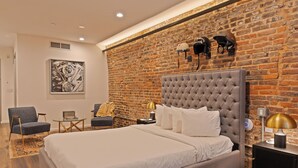 Un dormitorio moderno con una cama grande, un muro de ladrillo y un casco colgado.