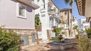 Un patio con una fuente, edificios blancos y una palmera.