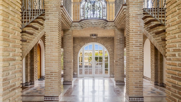 Un interior espacioso con un arco central, columnas de ladrillo y suelo de baldosas.