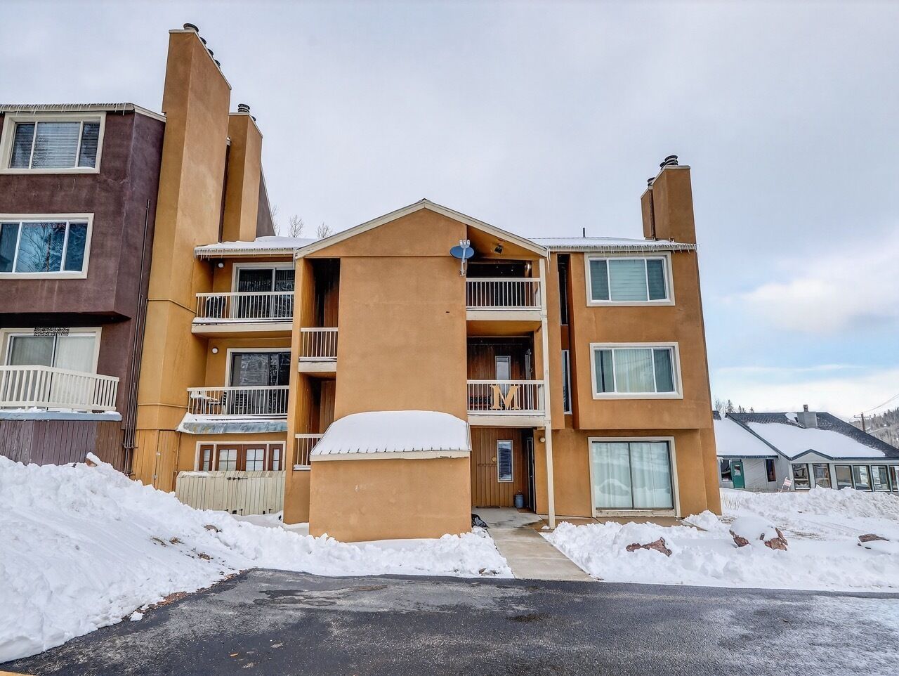 Un edificio de apartamentos de varios pisos con balcones y suelo cubierto de nieve.