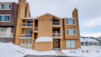 Un edificio de apartamentos de varios pisos con balcones y suelo cubierto de nieve.
