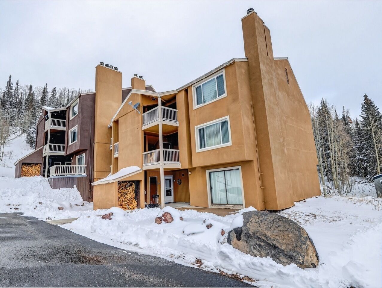 A multi-story building with balconies, large windows, and a snow-covered ground.